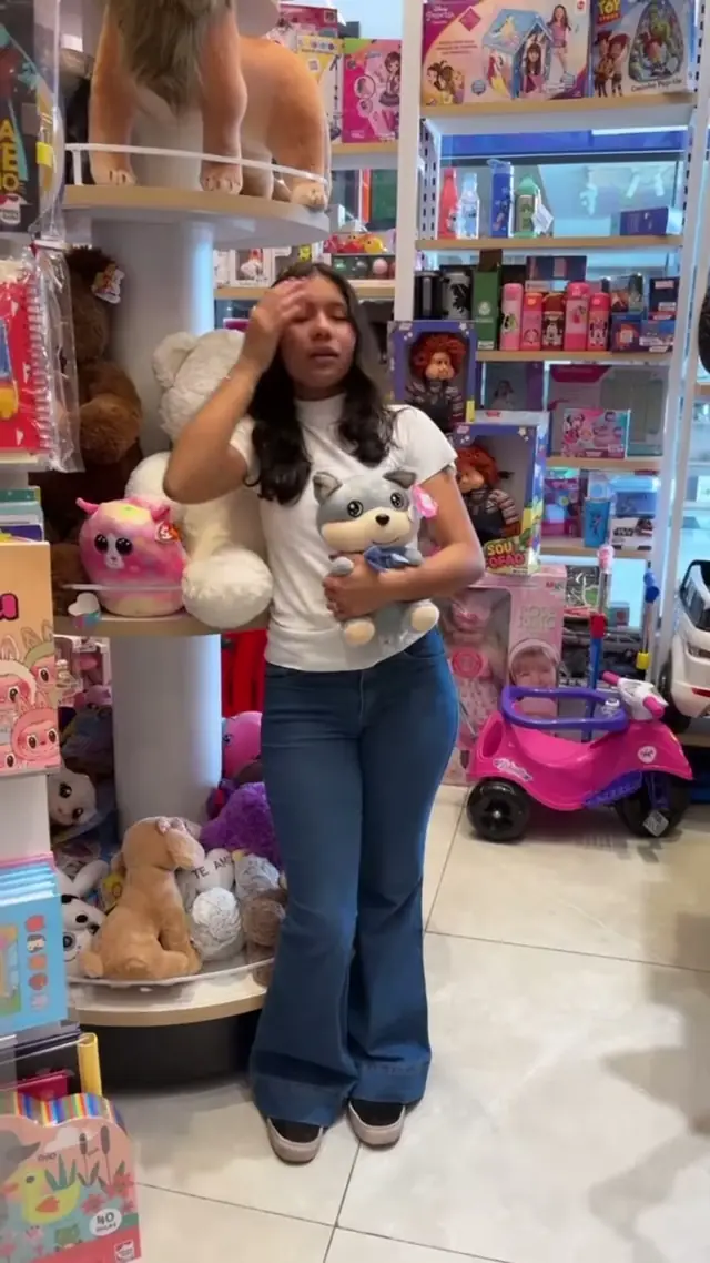 Atendente com pelúcias ao lado do expositor