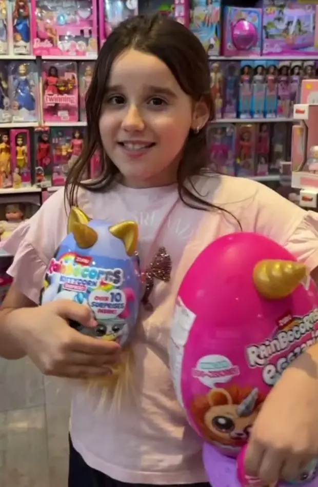 Menina sorrindo com brinquedos surpresa na loja
