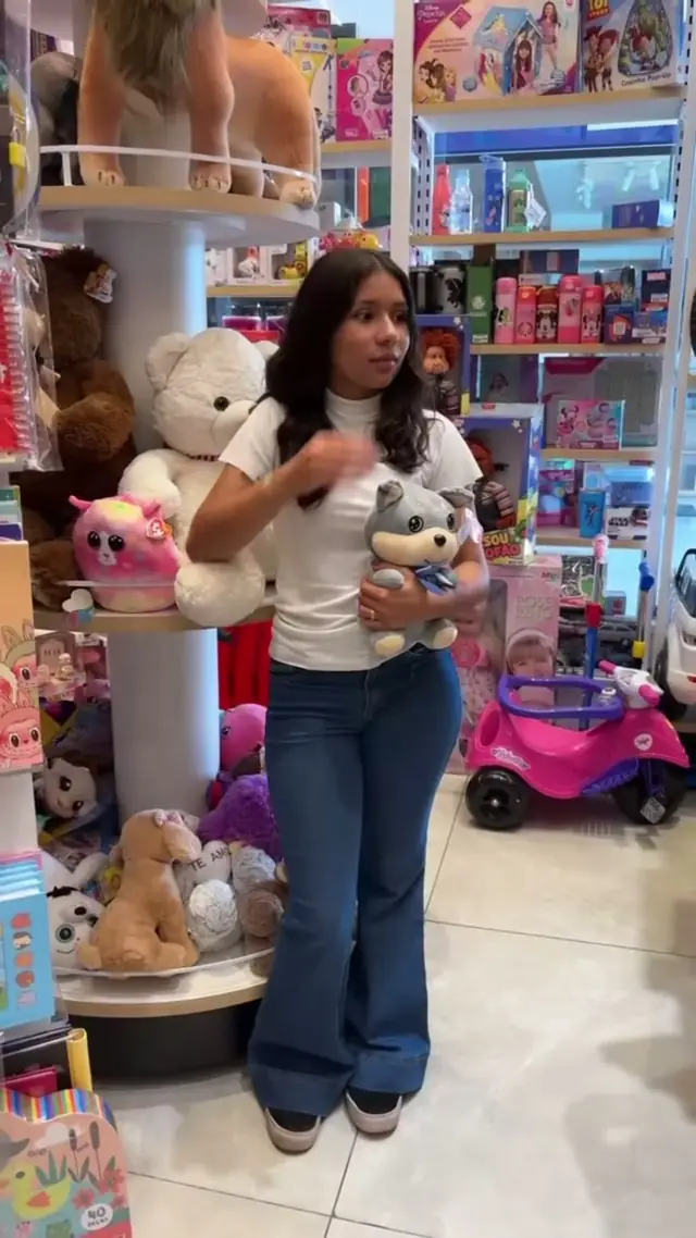 Atendente abraçando pelúcias ao lado do corredor